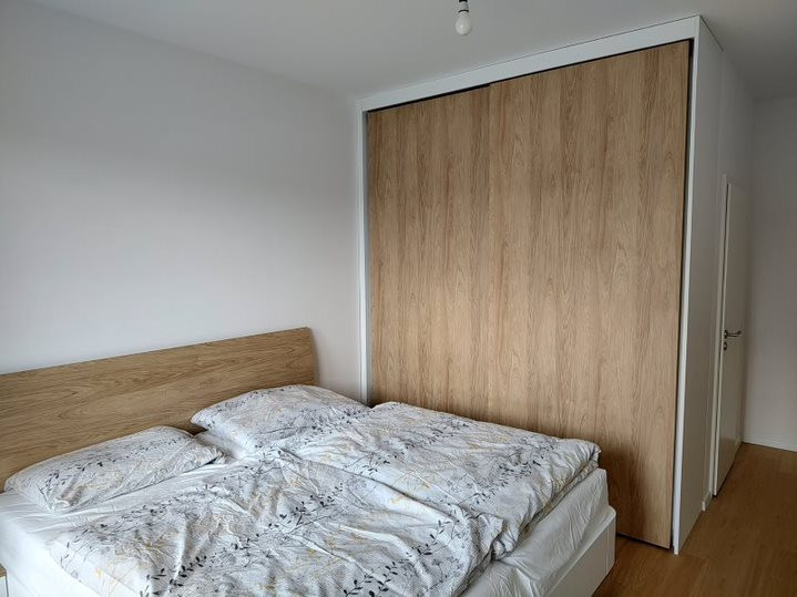 drevená manželská posteľ, doplnená o vstavanú skriňu so zasúvacími dverami
