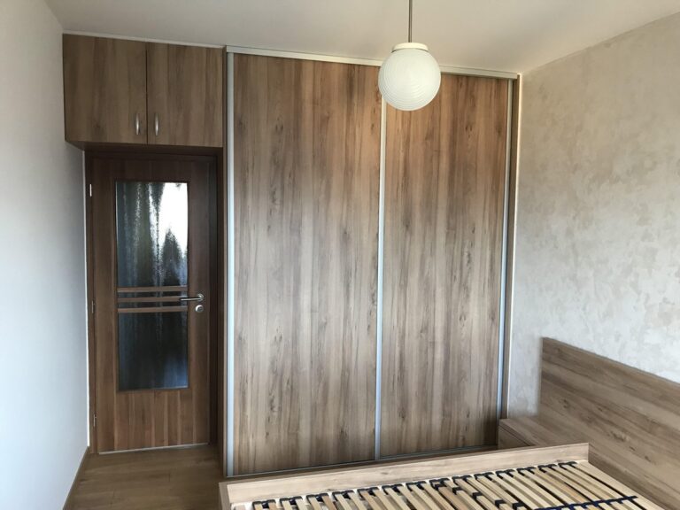 Drevená vstavaná skriňa na mieru s posuvnými dverami a úložným priestorom nad dverami